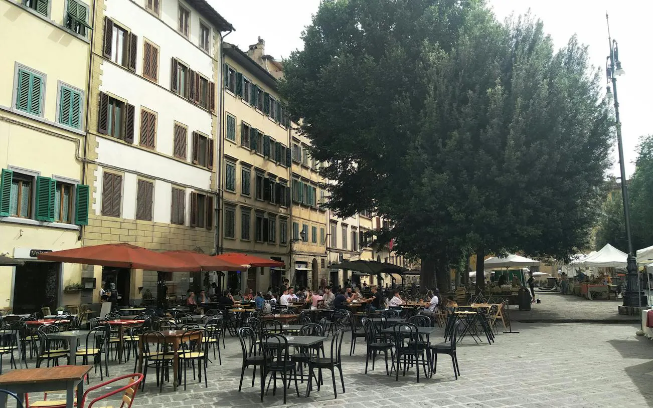 Outdoor café seating in a Florence square, part of the Detective Mystery self-guided city exploration game.