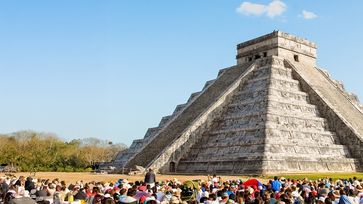 Crowd gathered at Chichen Itza during equinox, observing serpent shadow on pyramid.