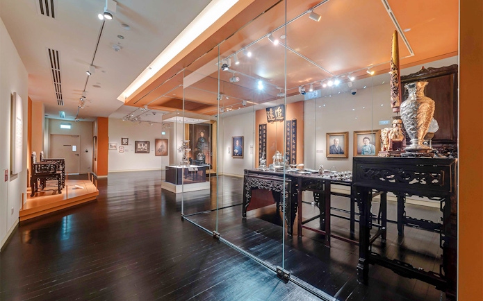 Peranakan Museum gallery with traditional artifacts and portraits on display.