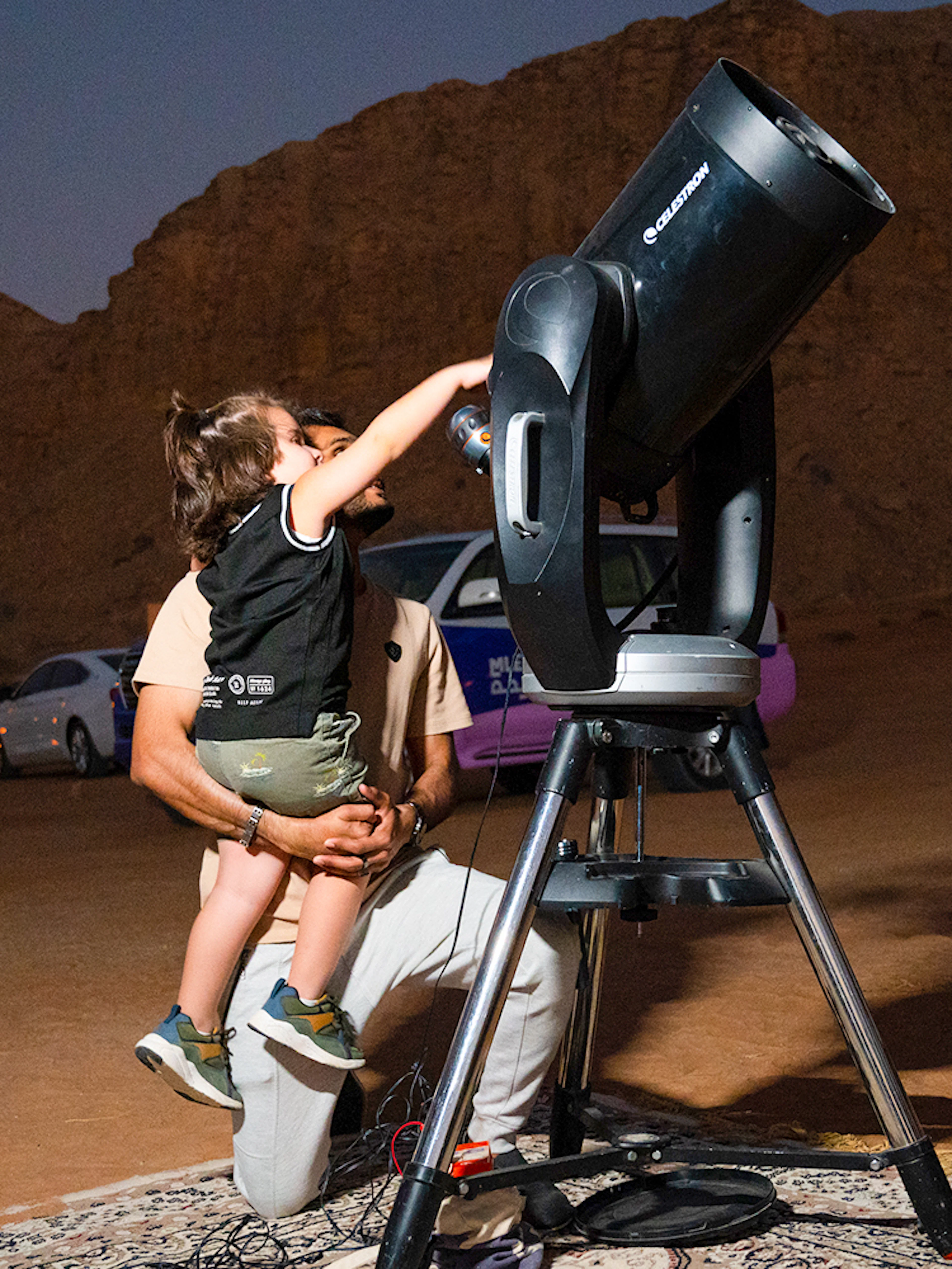 Child observing through telescope during stargazing in Mleiha desert.