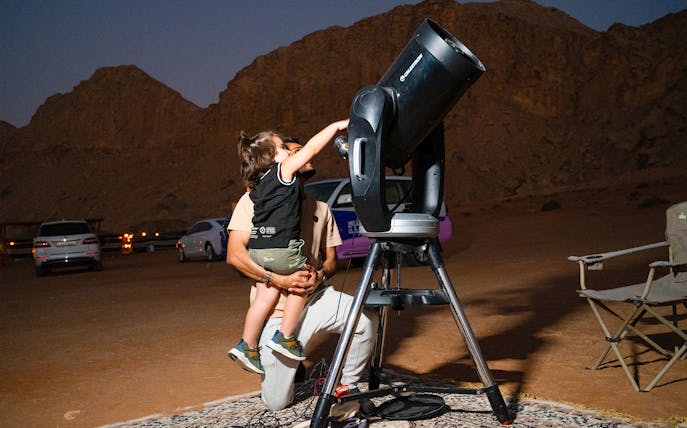 Child observing through telescope during stargazing in Mleiha desert.
