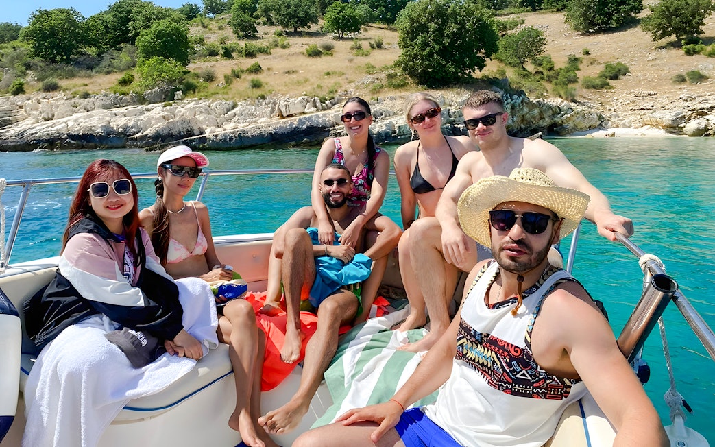 Group enjoying Saranda Boat Tour, Albania, with scenic coastline in the background.