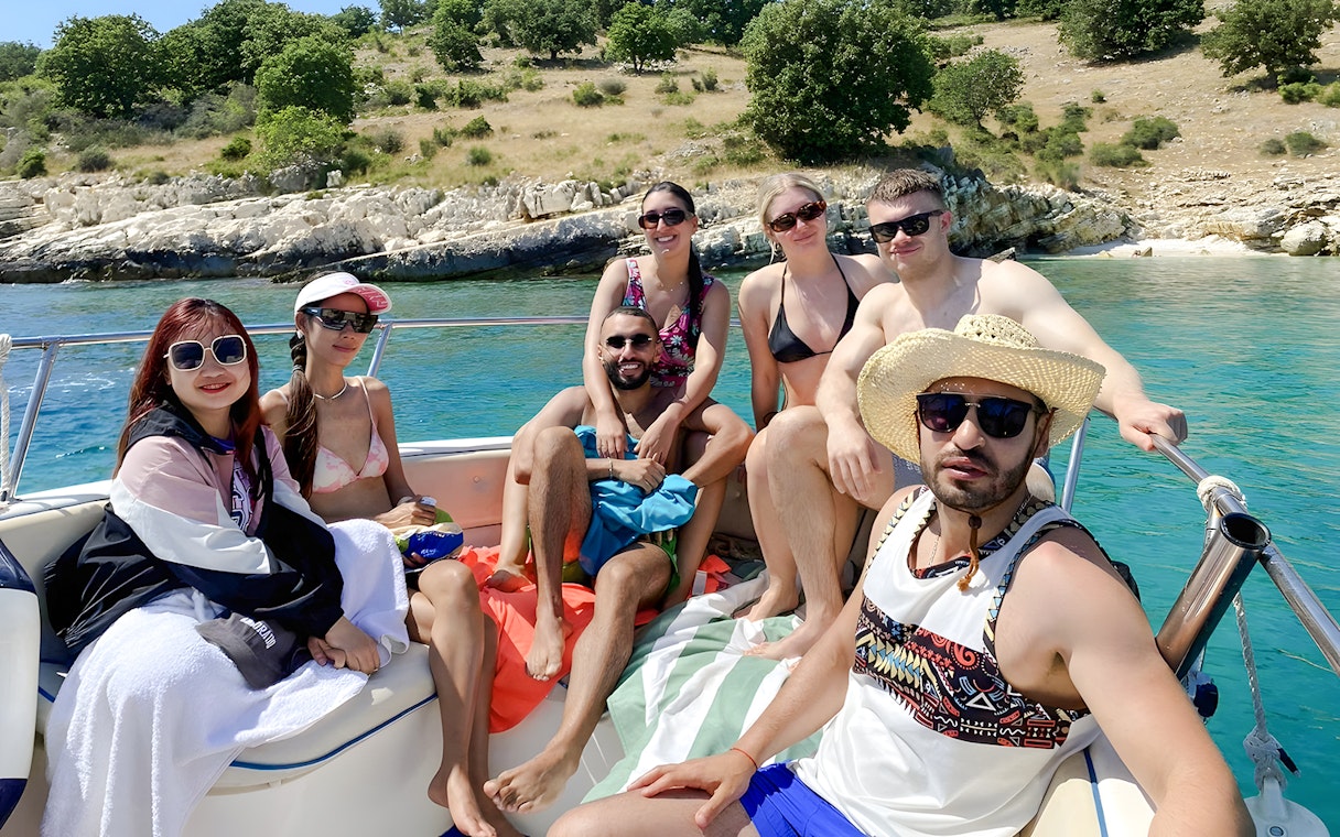 Group enjoying Saranda Boat Tour, Albania, with scenic coastline in the background.
