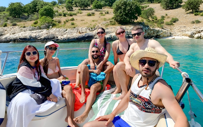 Group enjoying Saranda Boat Tour, Albania, with scenic coastline in the background.