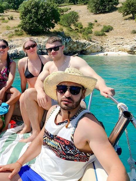 Group enjoying Saranda Boat Tour, Albania, with scenic coastline in the background.