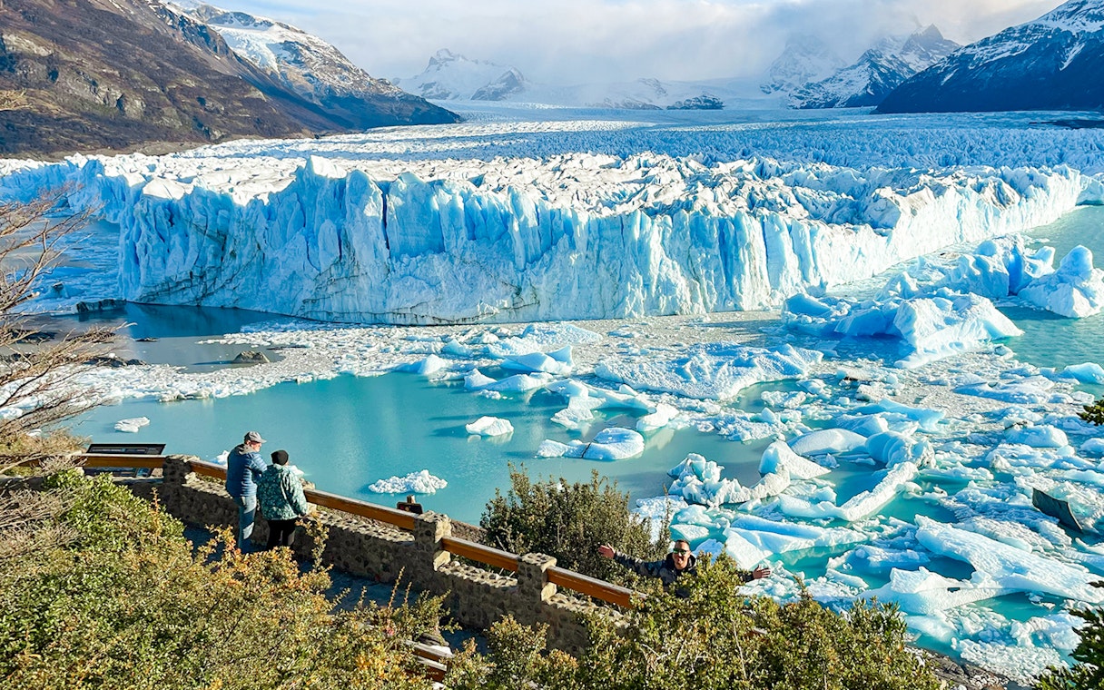 Visitors viewing the Perito Moreno Glacier in Argentina with icebergs floating in the turquoise water.