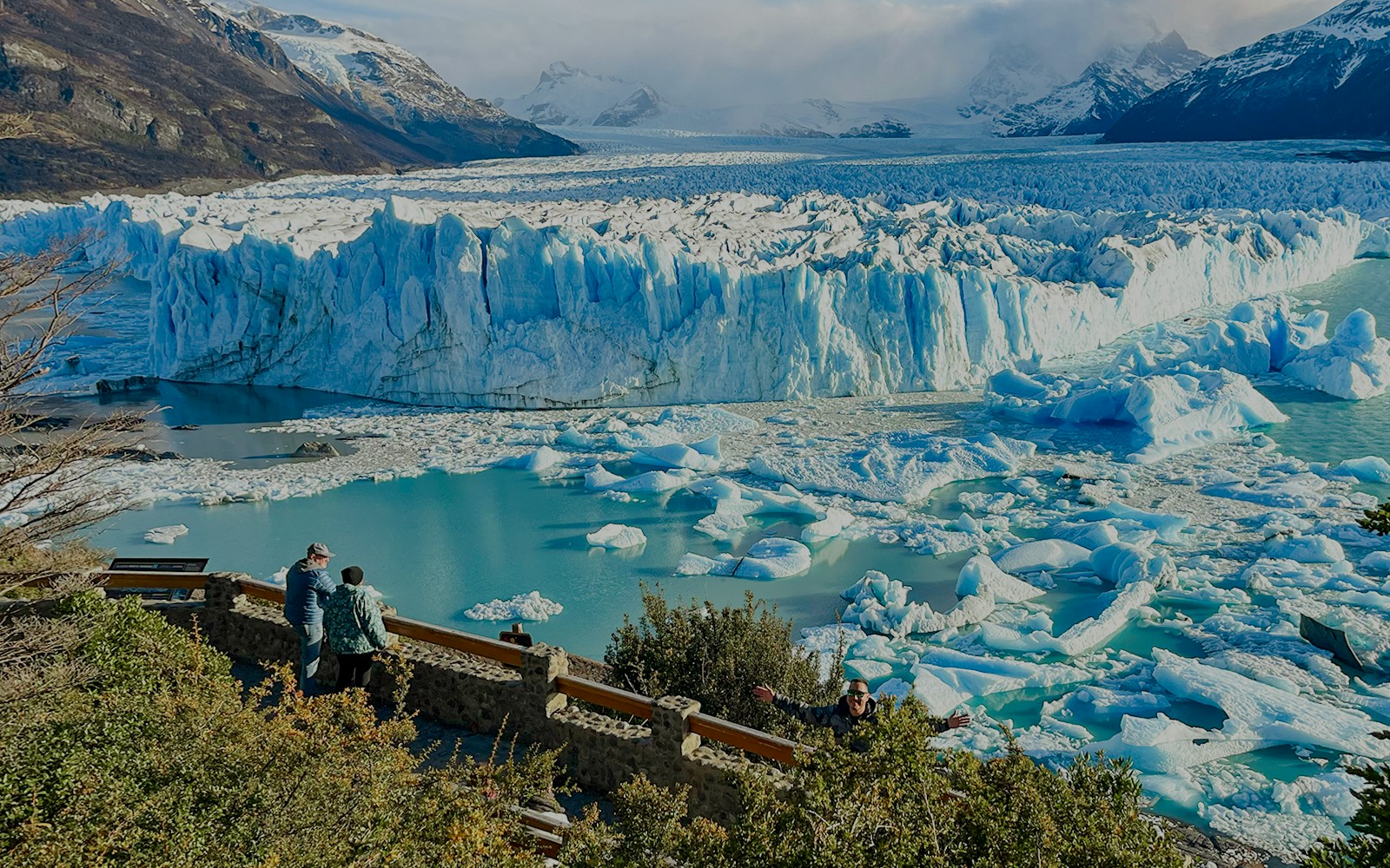 Visitors viewing the Perito Moreno Glacier in Argentina with icebergs floating in the turquoise water.