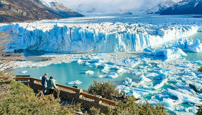 Visitors viewing the Perito Moreno Glacier in Argentina with icebergs floating in the turquoise water.