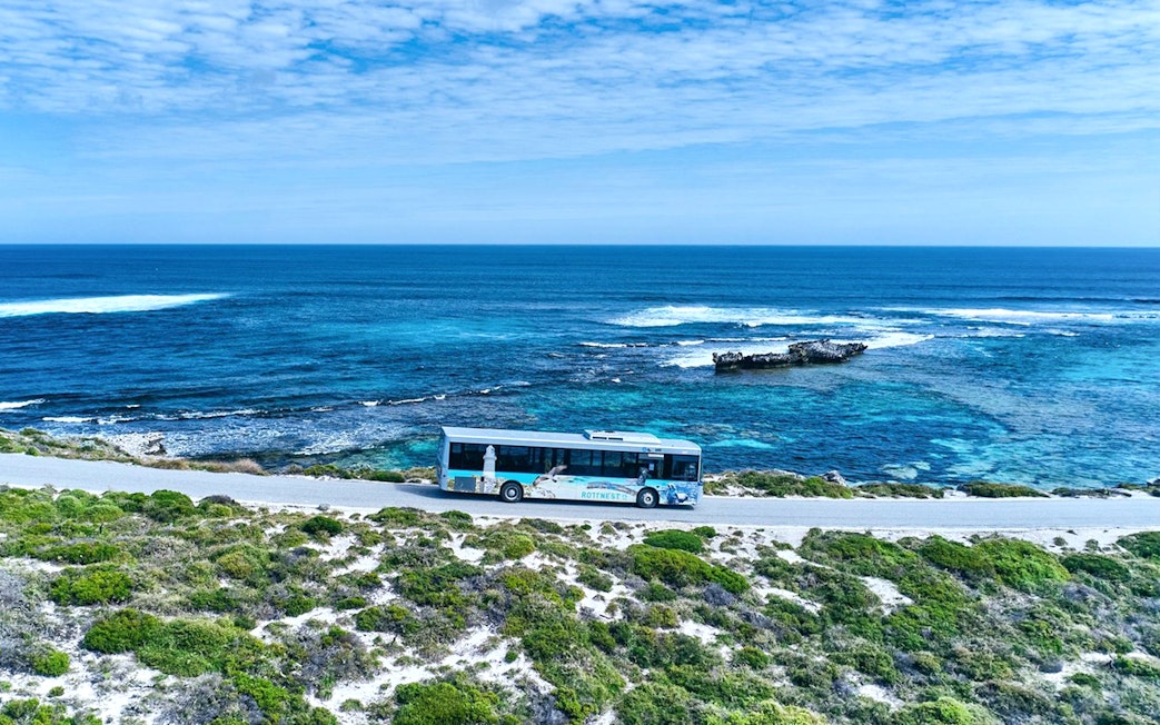Bus on coastal road with ocean view, Rottnest Island tour, Western Australia.