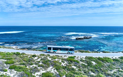 Bus on coastal road with ocean view, Rottnest Island tour, Western Australia.