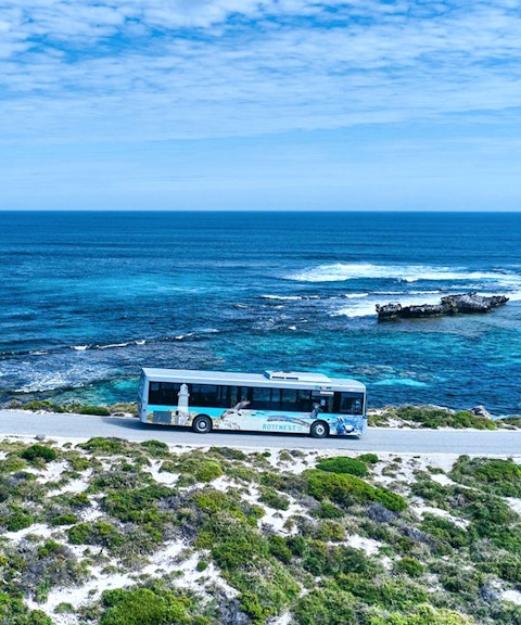 Bus on coastal road with ocean view, Rottnest Island tour, Western Australia.