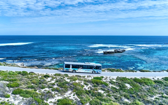 Bus on coastal road with ocean view, Rottnest Island tour, Western Australia.