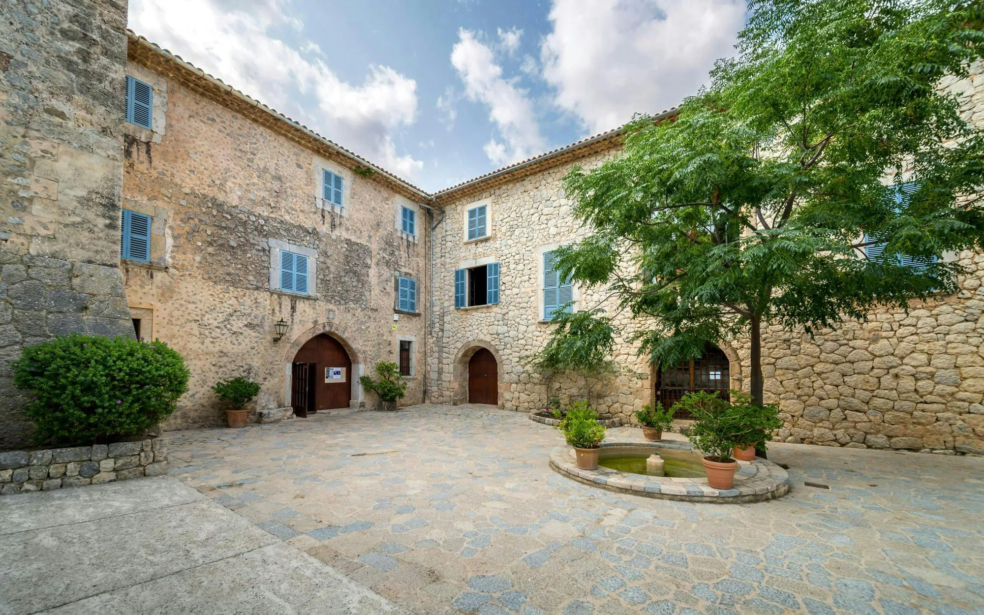 Courtyard of Son Marroig museum in Deià, Mallorca, with stone walls and potted plants.