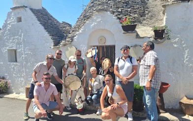 Tourists with tambourines in front of trulli houses in Alberobello, Italy.