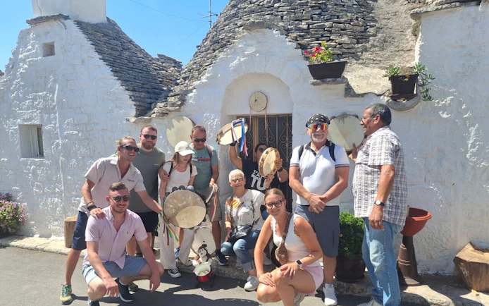 Tourists with tambourines in front of trulli houses in Alberobello, Italy.