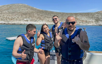 Group enjoying Heraklion catamaran cruise in life vests with scenic coastal backdrop.