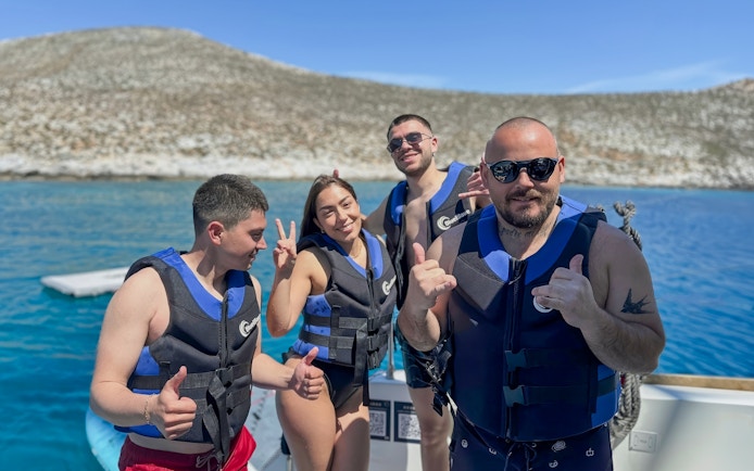 Group enjoying Heraklion catamaran cruise in life vests with scenic coastal backdrop.