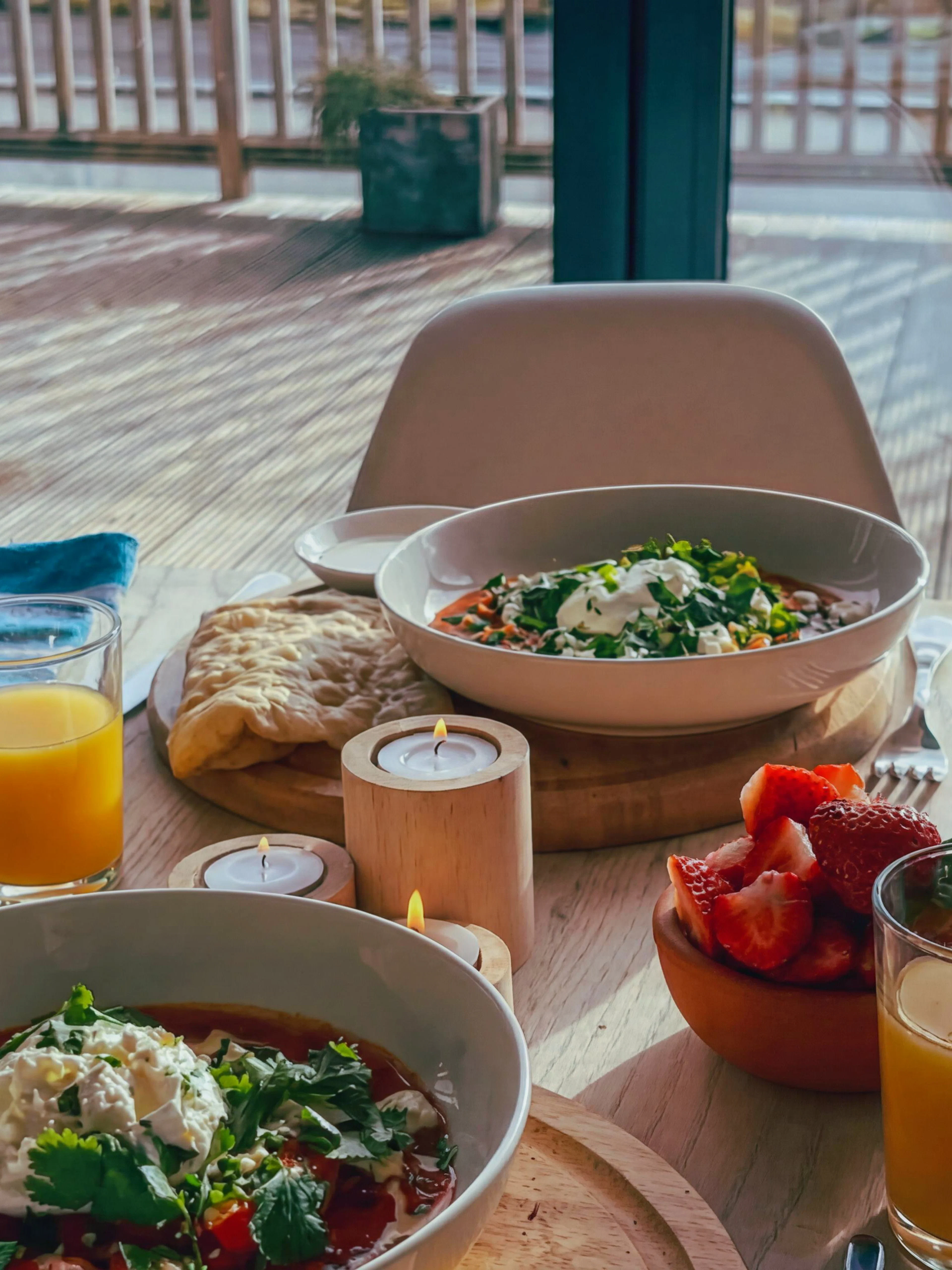 Hotel breakfast with fresh fruit, orange juice, and sparkling wine on a sunlit terrace.