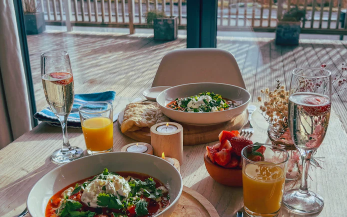 Hotel breakfast with fresh fruit, orange juice, and sparkling wine on a sunlit terrace.