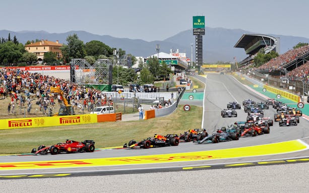 Formula 1 cars racing at Circuit de Barcelona-Catalunya with spectators in the stands.