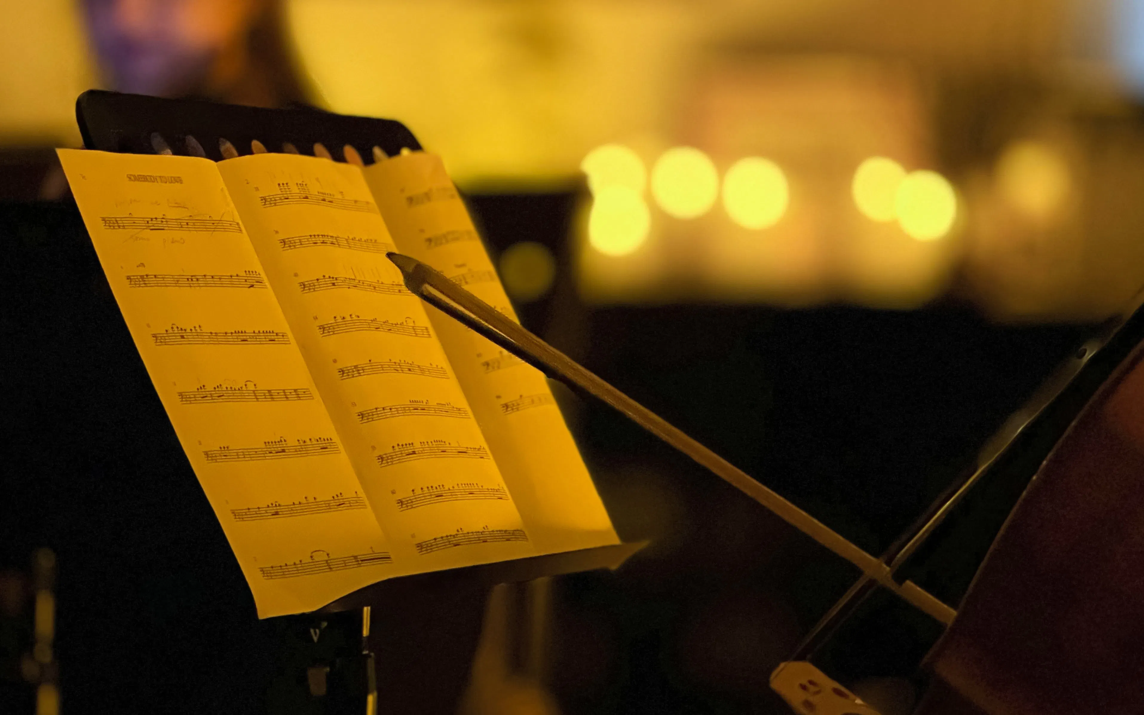 Sheet music and cello bow at candlelit Queen performance, Chopin Gallery, Krakow.