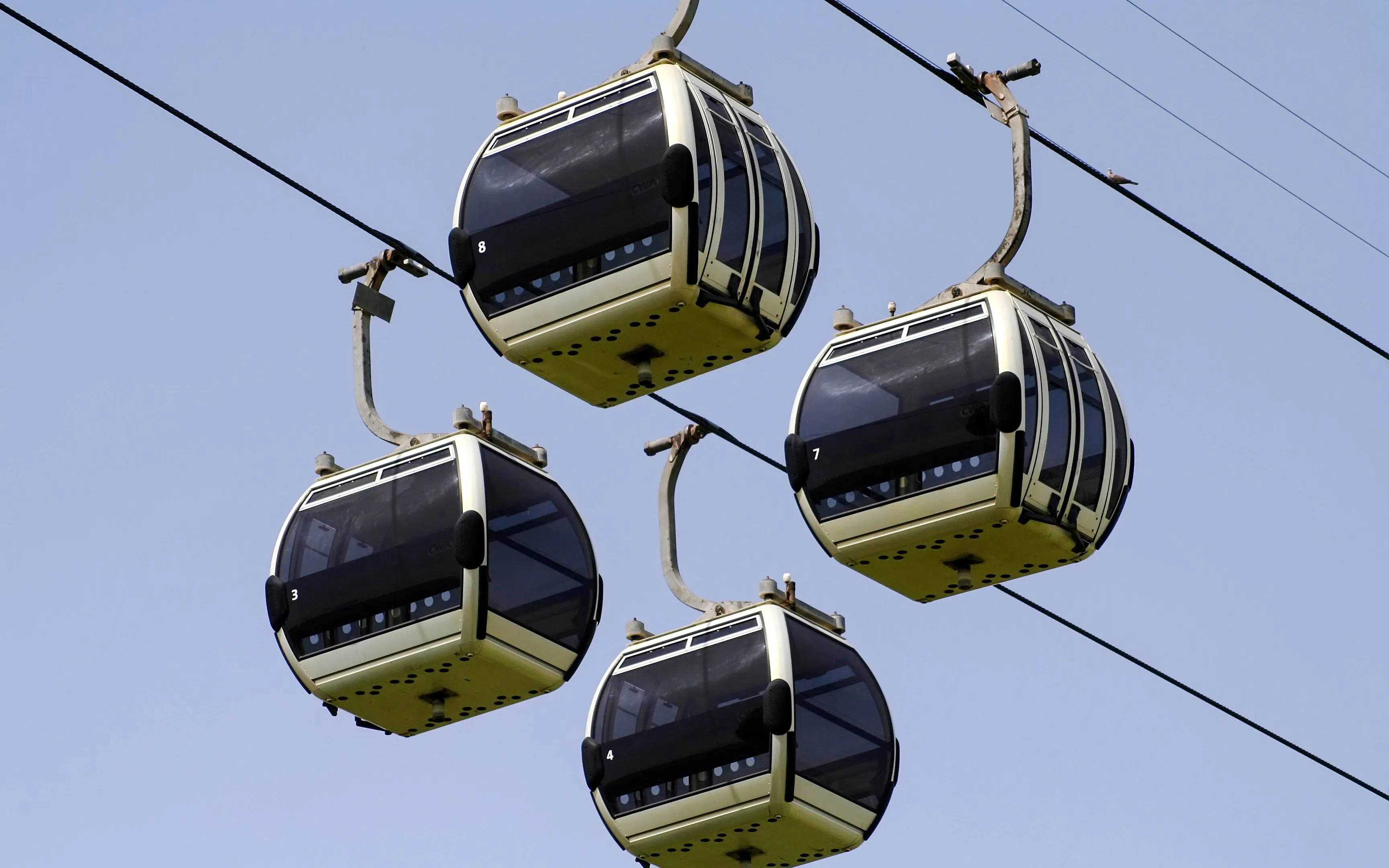 Dubai cable cars suspended in the sky against a clear blue backdrop.