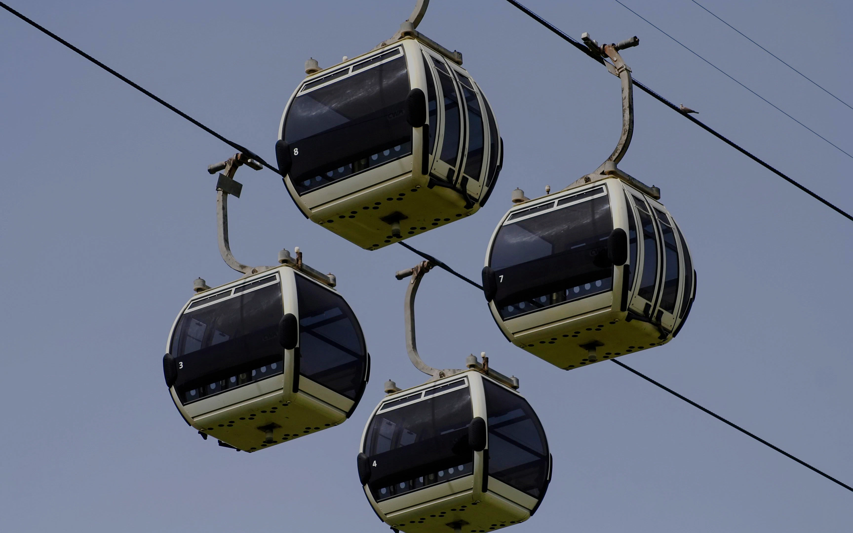 Dubai cable cars suspended in the sky against a clear blue backdrop.