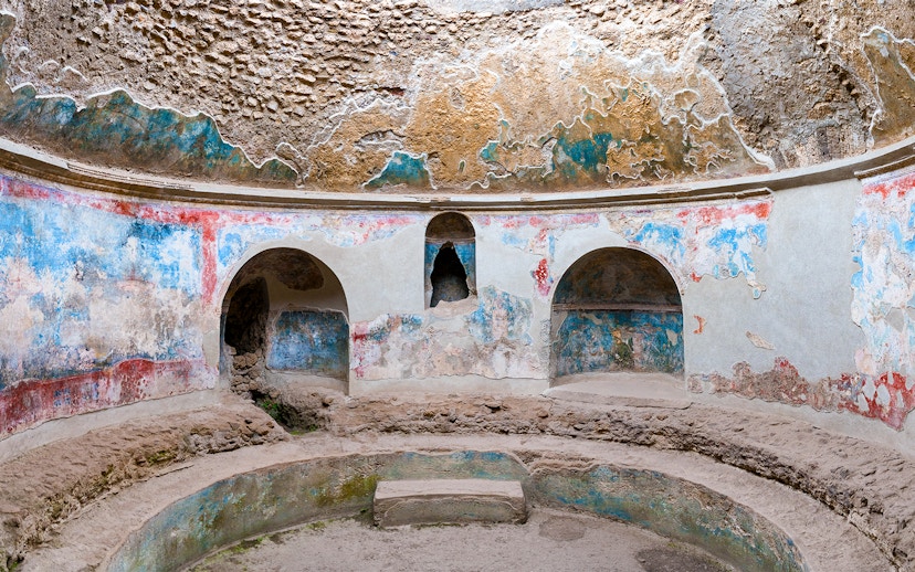 Pompeii Baths ancient frescoes and stone seating in circular room.