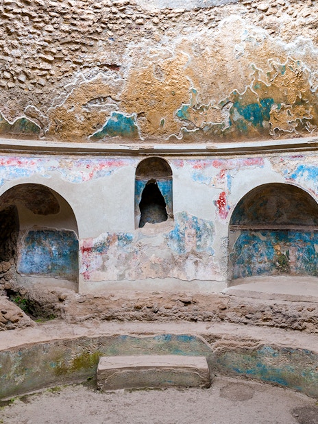 Pompeii Baths ancient frescoes and stone seating in circular room.