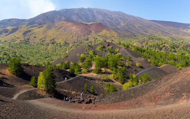 Mount Etna north slopes with side crater and hikers on volcanic terrain.