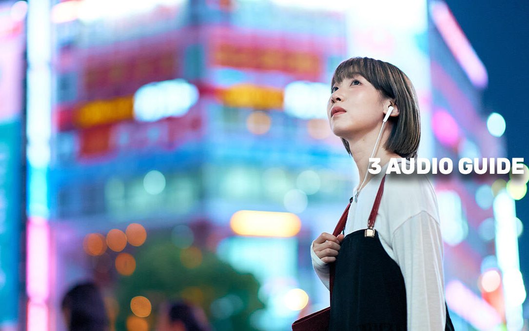 Person with earphones exploring Tokyo at night with neon lights.