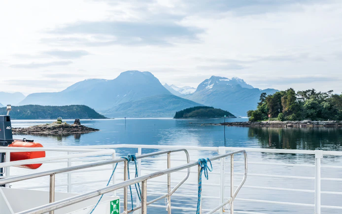 Boat deck view of Ålesund-Geiranger fjord with distant mountains and calm water.
