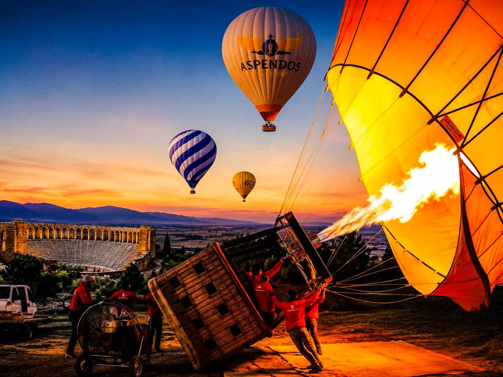 Hot air balloons inflating at sunrise near Aspendos amphitheater, Antalya.