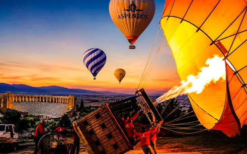Hot air balloons inflating at sunrise near Aspendos amphitheater, Antalya.