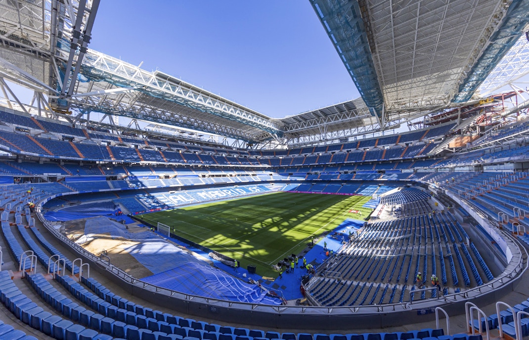 Santiago Bernabeu Stadium interior with empty seats and green field, Madrid.