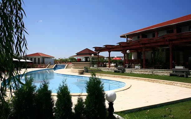 Resort poolside view in Danube Delta with outdoor seating and clear sky.