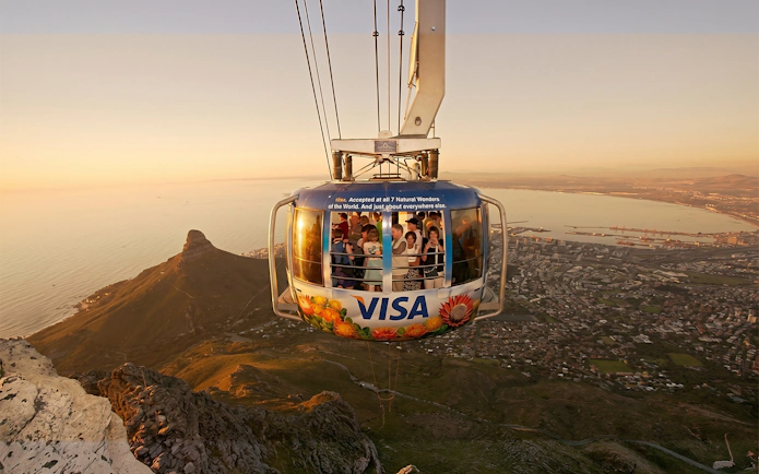 Cable car ascending Table Mountain with Cape Town cityscape below.