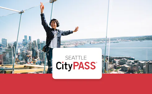 Woman standing on Seattle Space Needle's observation glass with city skyline.