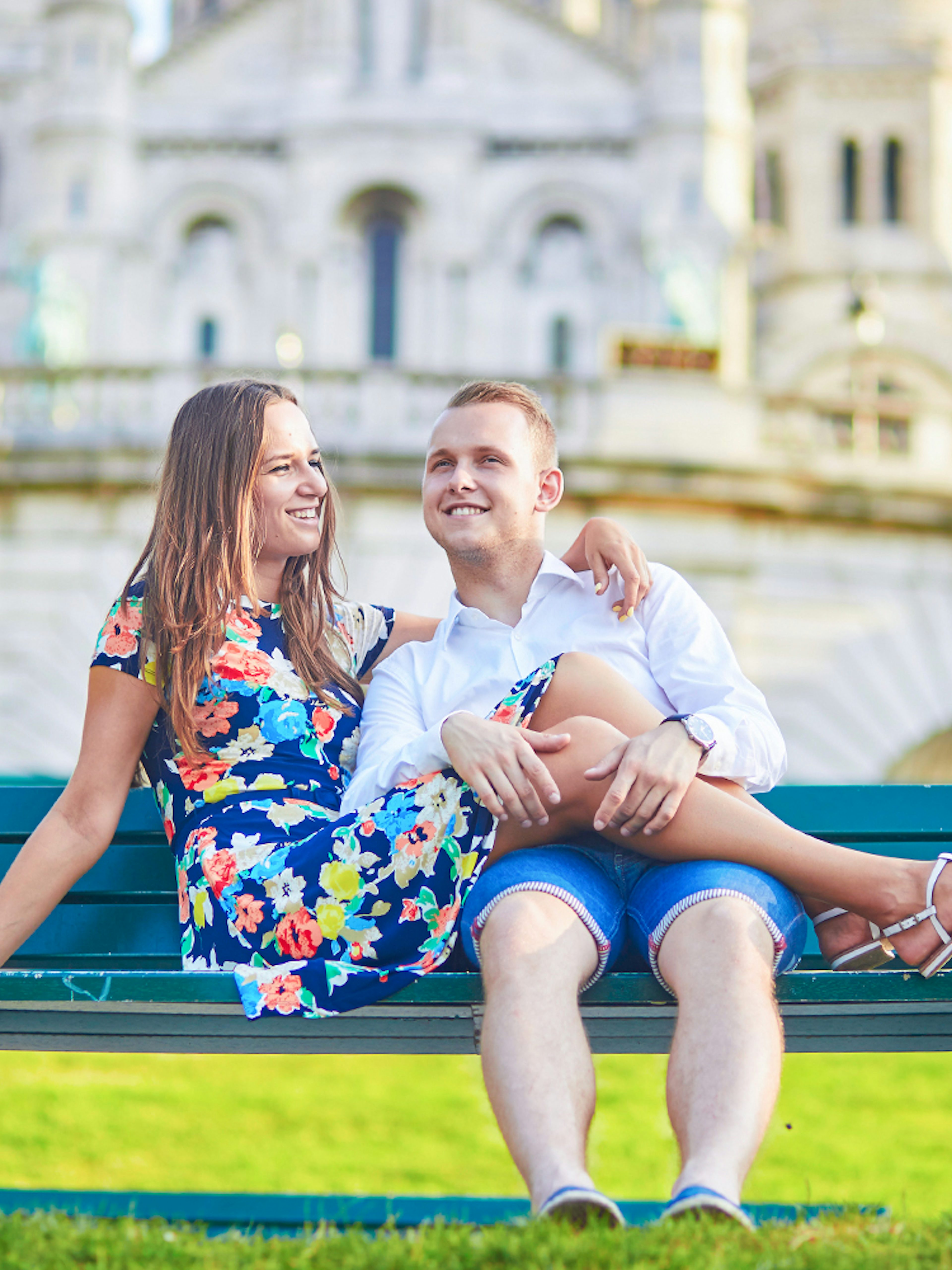 Couple sitting on a bench in front of Sacré-Cœur Basilica, Montmartre, Paris.