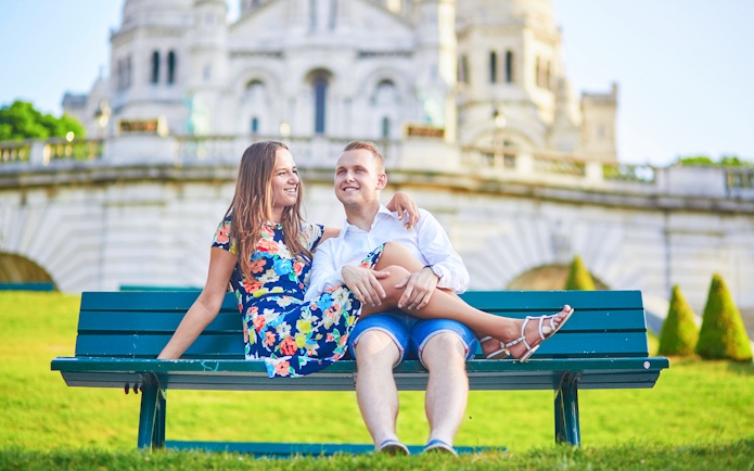 Couple sitting on a bench in front of Sacré-Cœur Basilica, Montmartre, Paris.