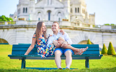 Couple sitting on a bench in front of Sacré-Cœur Basilica, Montmartre, Paris.