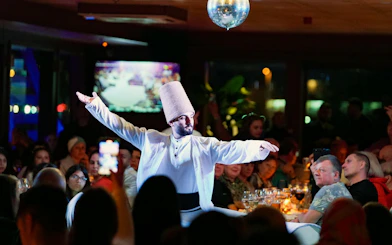 Dancer performing traditional dance on Bosphorus dinner cruise at night.
