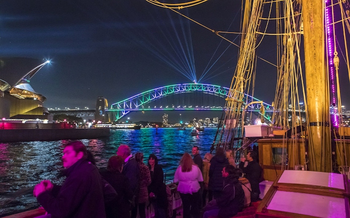Tall ship cruise with people enjoying views of Sydney Harbour Bridge and Opera House during Vivid Sydney.