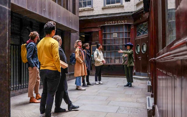 Tour group listening to a guide outside Simpsons in London on the Heart of 'The City' Food Tour.