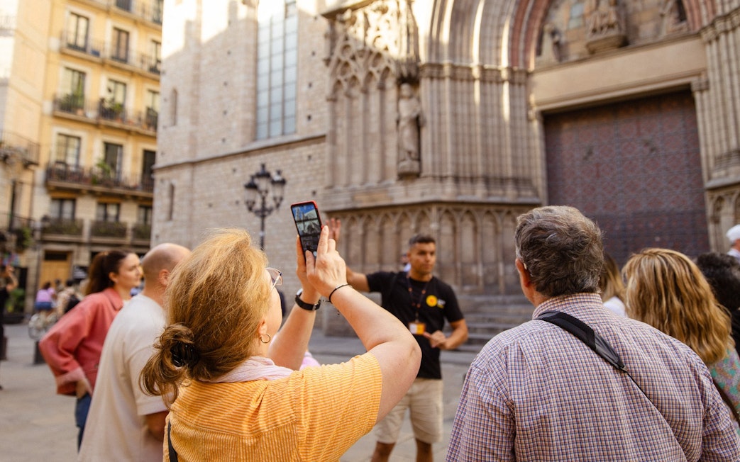 Tourists listening to a guide in front of a historic building in Barcelona.