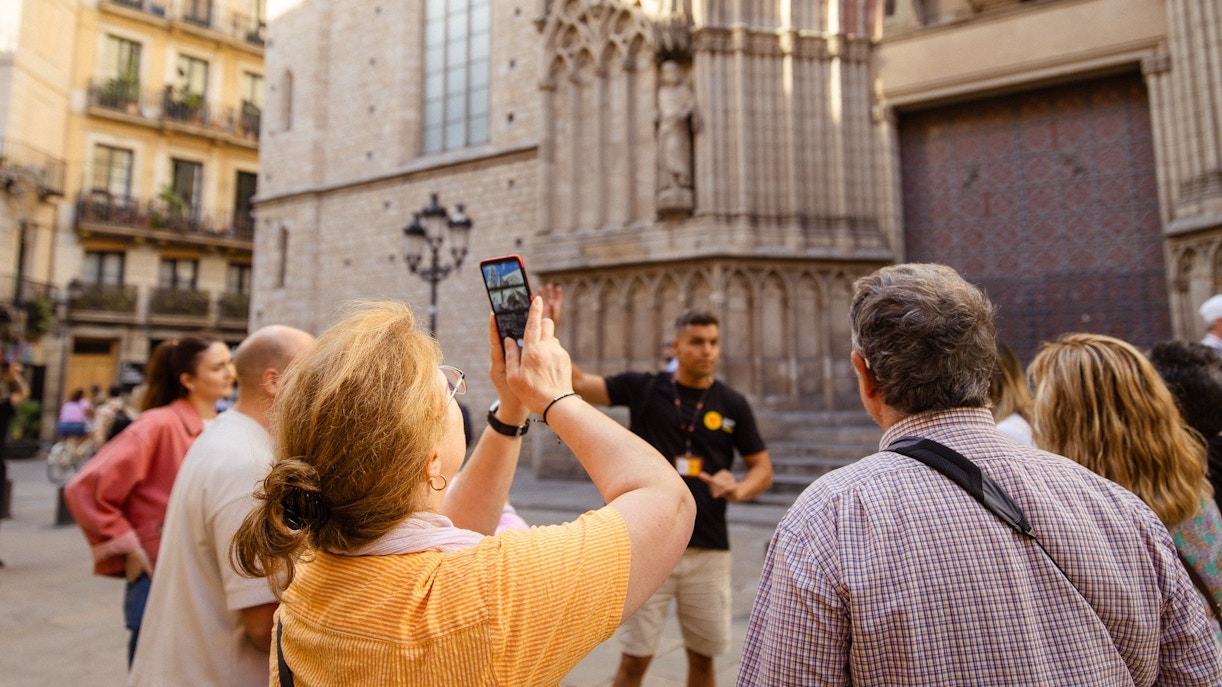 Tourists listening to a guide in front of a historic building in Barcelona.