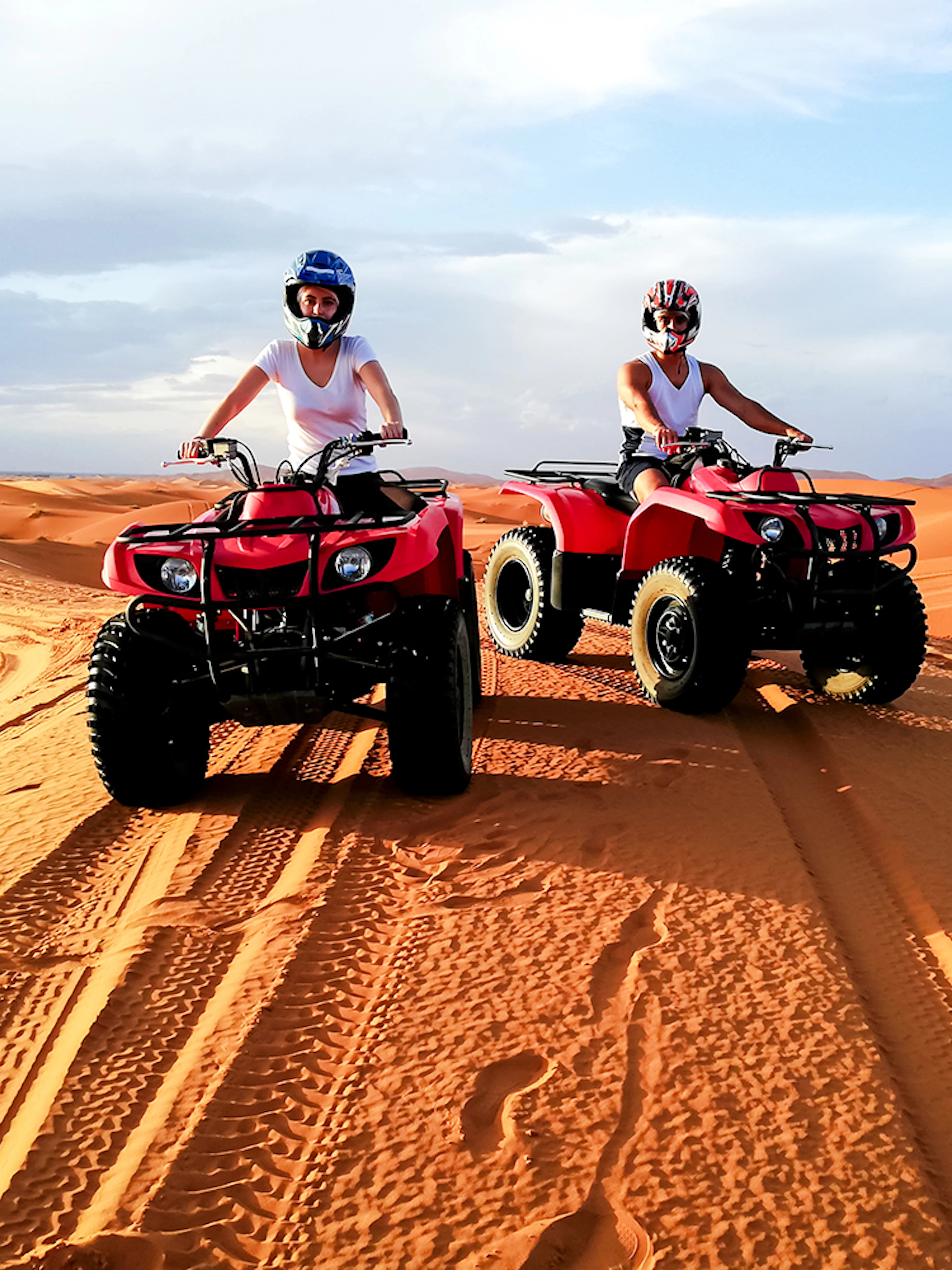 People riding quad bikes on sand dunes in Agafay Desert, Marrakech.