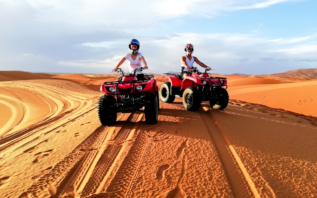 People riding quad bikes on sand dunes in Agafay Desert, Marrakech.