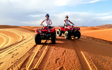 People riding quad bikes on sand dunes in Agafay Desert, Marrakech.