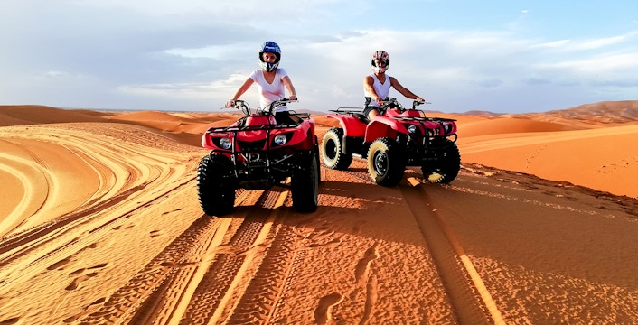 People riding quad bikes on sand dunes in Agafay Desert, Marrakech.